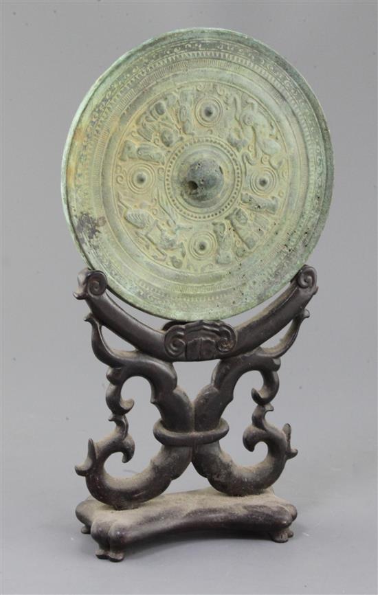 A Chinese bronze circular mirror, Han dynasty or later 18cm diameter, wood stand